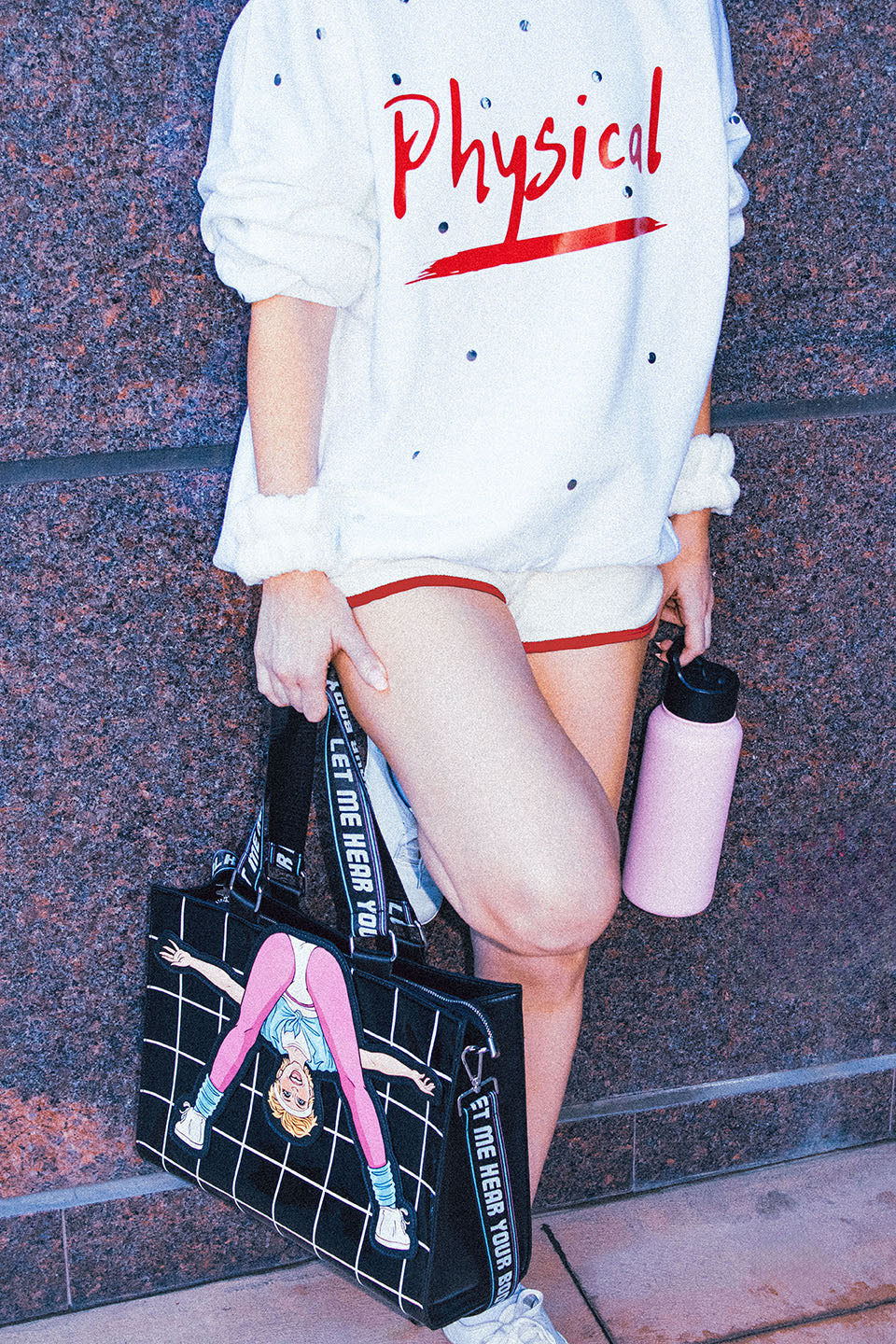 Woman Standing Holding Graphic Tote Bag with Olivia Newton-John Illustration and Physical Let Me Hear Your Body Talk Lyrics