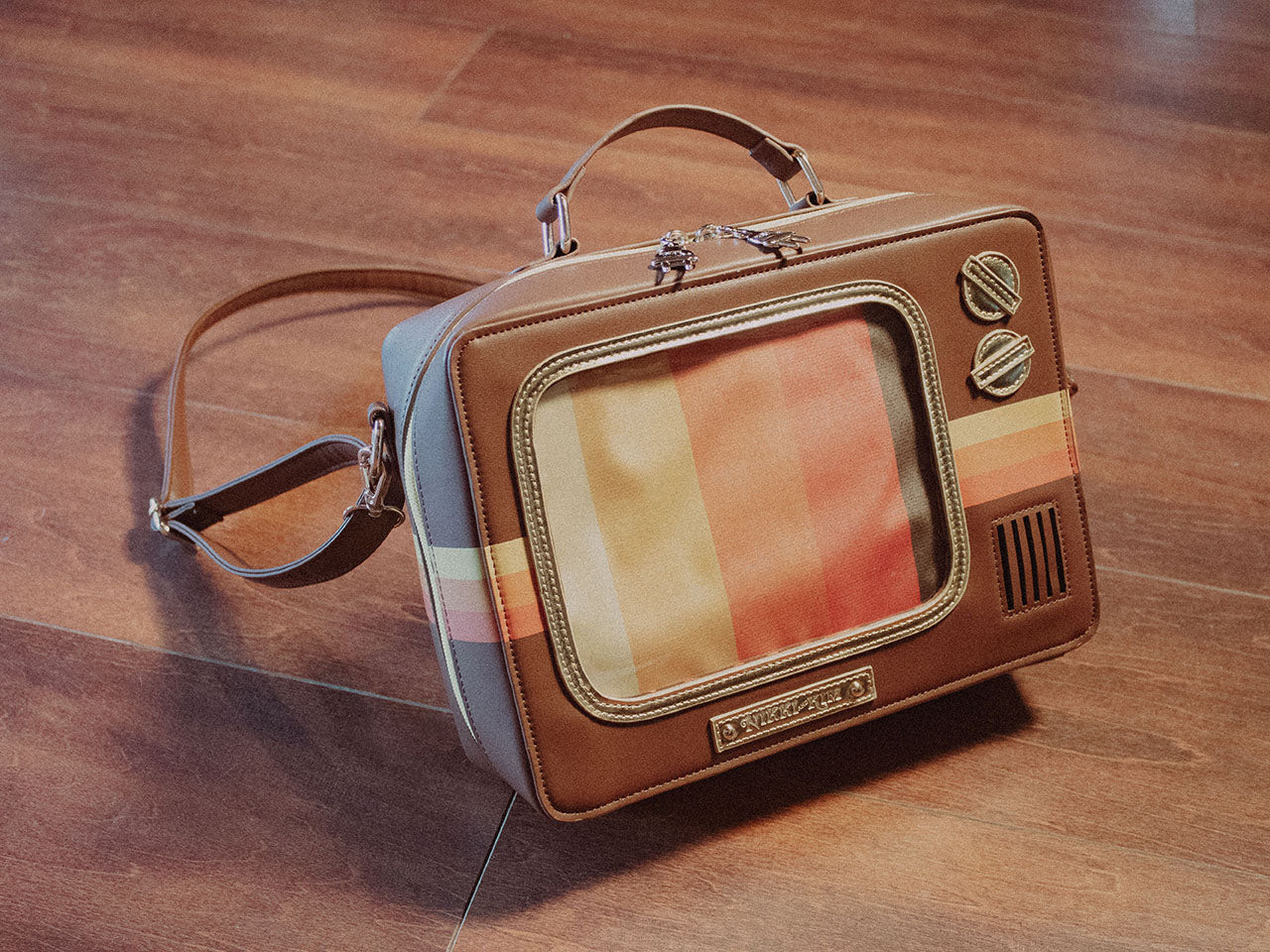 Retro TV Purse Inspired by Wood Paneled 1970's Television Consoles with Color Stripes and Interchangeable Screens on Wood Floor