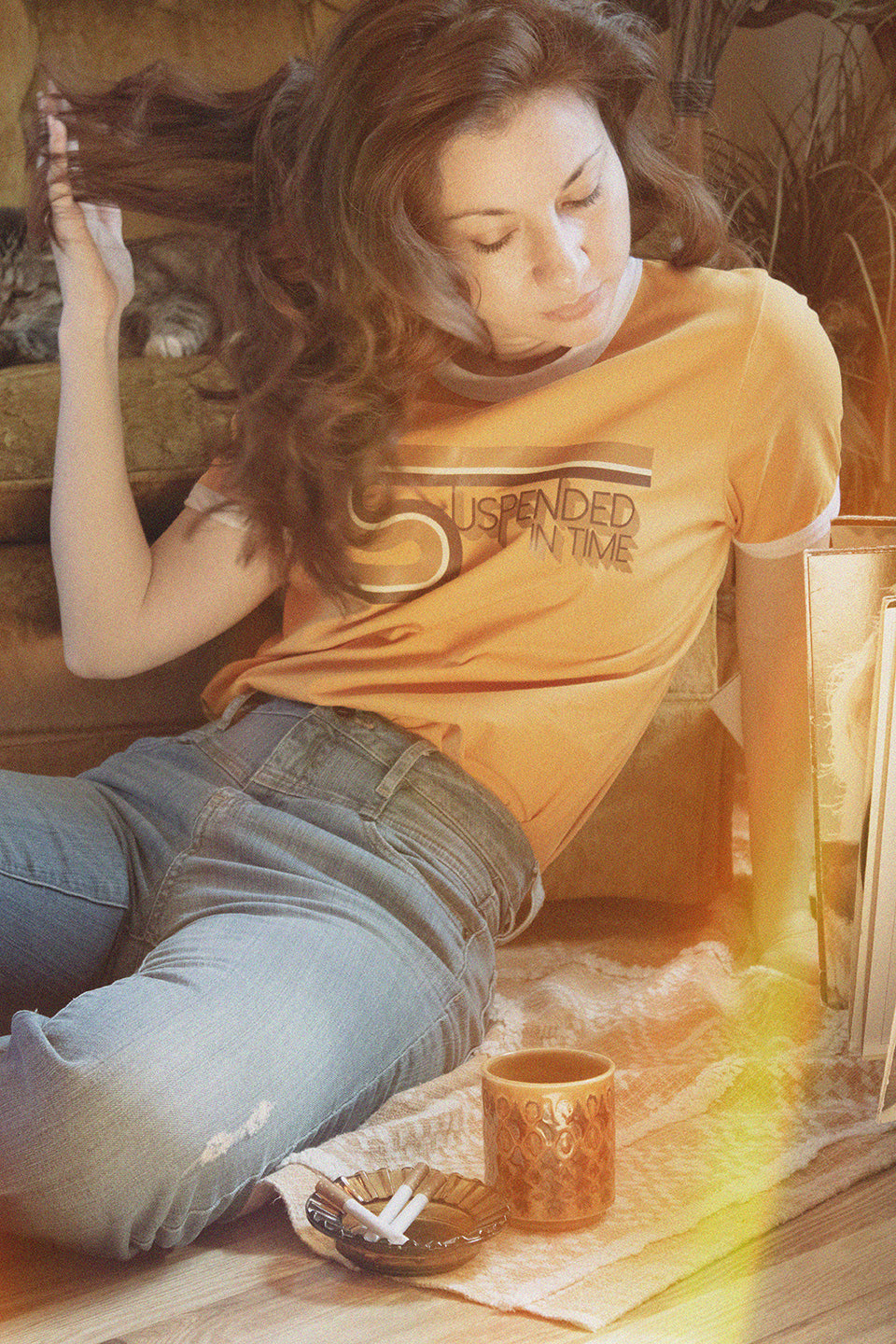 Woman Lounging Wearing Graphic 1970’s Style Ringer T-Shirt with Suspended In Time Song Lyrics from Xanadu Movie