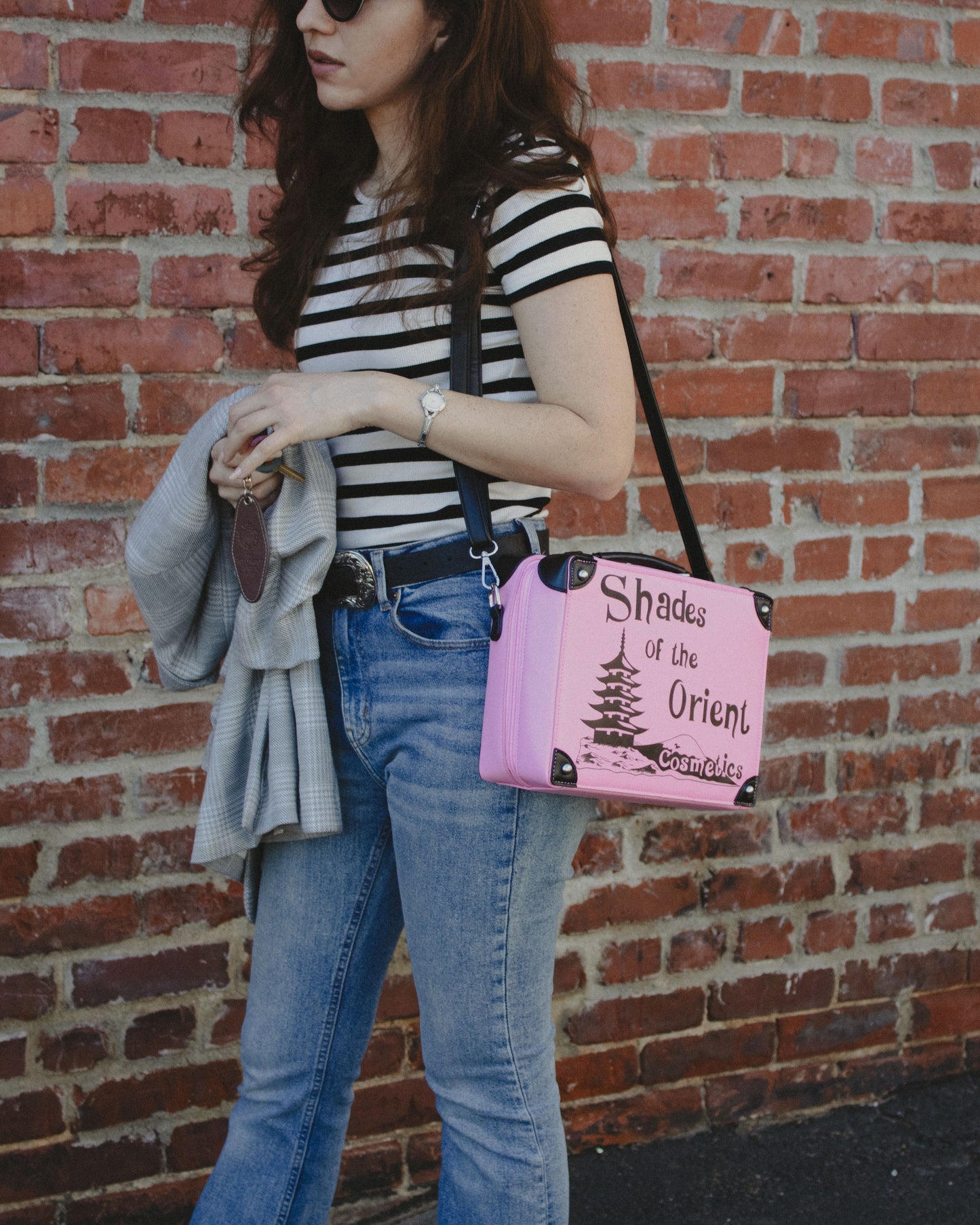 Woman Wearing Prop Replica Purse of TV Series The Nanny Pink Shades of the Orient Cosmetics Makeup Case next to Brick Wall